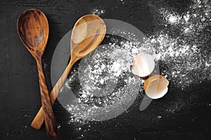 Pile of flour in wooden spoon on dark background