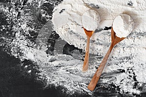 Pile of flour in wooden spoon on dark background