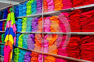 Pile of folded colourful t-shirts clothes in a shop.