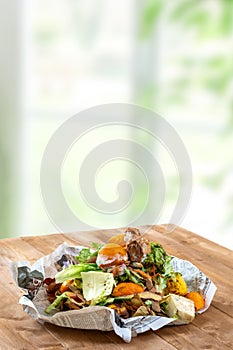 A pile of food waste, such as eggshells and fruit and vegetable peels, on a paper and wooden table kitchen background photo