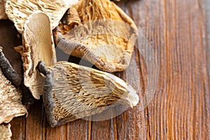 A pile of forest aromatic edible dried mushrooms on a wooden dark background.