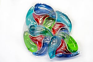 A pile of Four-color laundry detergent capsules on a light background, close-up, selective focus.