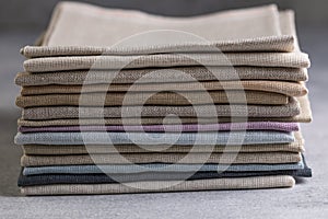 A pile of four folded dull-colored natural linen fabric, close up