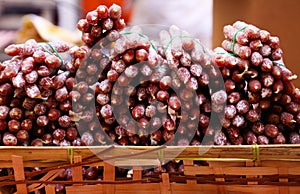 Pile of French mini salamis provencale presented in wood box  on farmer market - St. Tropez, France