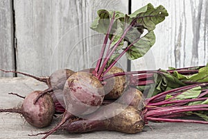 a pile of fresh beets with tops on a wooden background, horizontal photo