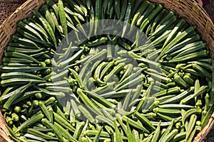 A pile of fresh green okra or lady\'s finger arranged neatly in a wicker basket
