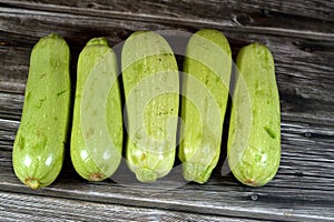 Pile of fresh green zucchini or courgette vegetables  on wooden background, selective focus of fresh raw organic squash