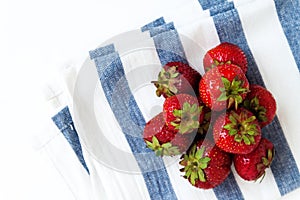 Pile of fresh juicy strawberries on towel in blue stripes, top v