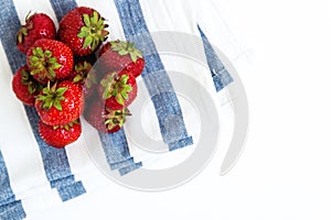 Pile of fresh juicy strawberries on towel in blue stripes, top v