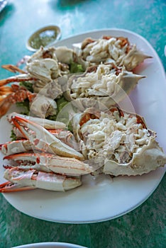 A pile of fresh meaty steam crabs served on a white plate at a seafood restaurant in Thailand