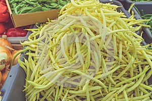 Pile of fresh organic vegetables, yellow beans on display at farmer market. Vegan and bio food concept.