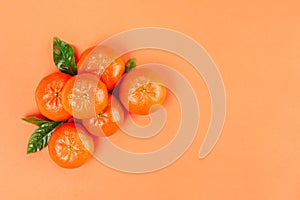 Pile of fresh ripe mandarins with green leaves on orange background. Copy space