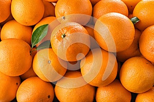 Pile of fresh ripe oranges with leaves as background