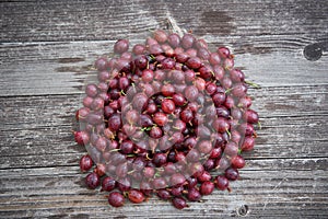 Pile of freshly riped red gooseberries on old wooden table