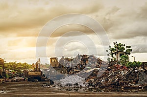 Pile of garbage and backhoe at waste depot. Rubbish recycling business. Heap  of plastic waste, wood scrap, and old rusty metal at