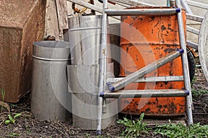 A pile of garbage from a broken gray metal stepladder with a red barrel and pieces of iron