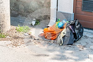 Pile of garbage and home junk left in the front of the house in the street in plastic bags for dumper truck to collect