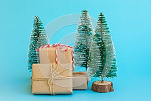 Pile of gift boxes wrapped in craft paper tied with twine red white ribbon Christmas trees on mint blue background. New Year