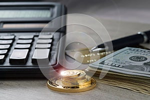 A pile of gold coins, dollar bills, gold credit card, pen and a calculator photo