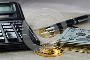 A pile of gold coins, dollar bills, gold credit card, pen and a calculator photo