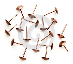 A pile of gold-colored upholstery nails on a white background