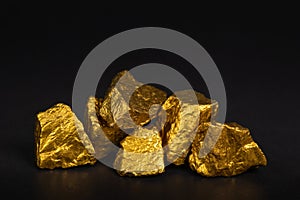 A pile of gold nuggets or gold ore on black background, precious photo