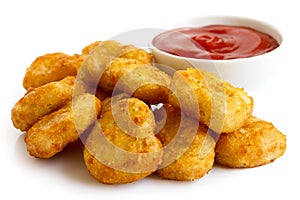 Pile of golden deep-fried battered chicken nuggets with bowl of