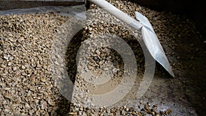 A pile of gray rubble with a shovel and small stones in the room. Crushed stone with a shovel, close-up.