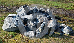 Pile of gray stones in the meadow. workers are catching stones to use on a rock garden in the park. quarry unworked irregular piec