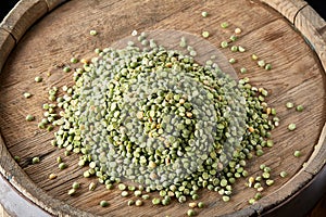 Pile of green peas on the top of wooden barrel, close-up, top view, selective focus.