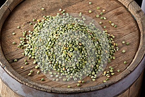 Pile of green peas on the top of wooden barrel, close-up, top view, selective focus.