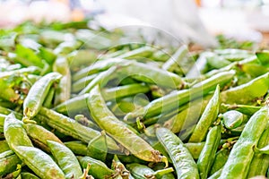 Pile of green snap peas pea pods being sold at a farmer`s market