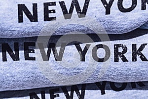 Pile of grey cotton sweatshirts with printed inscription - New York, exposed on tourist shop. Visiting NY conception.