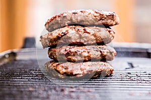 Pile of grilled ground beef patties on BBQ photo