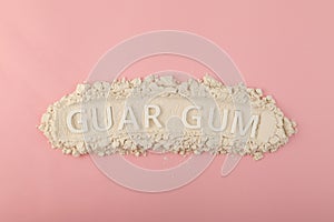 Pile of Guar gum powder or guaran on pink background. Food additive E412. Inscription GUAR GUM. Design element. Thickening agent.