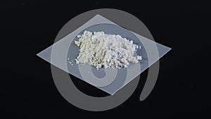 Pile of Guar gum powder or guaran rotating anticlockwise on dark background. Food additive E412.