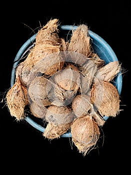 Pile of hairy coconut on plastic tub, on black background