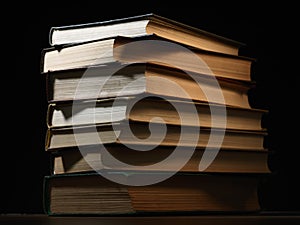 Pile of hardcover books in a shadowy room