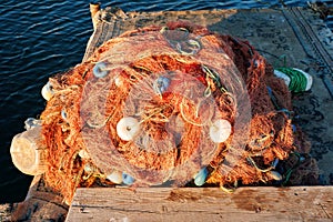 Pile of industrial fishing net with buoy on the wooden doc