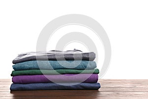 Pile of ironed clothes on table against white background