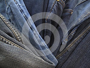 Pile of jeans background. Heap of old jeans. Stack of blue jeans. Blue grunge background. Casual style of clothes.