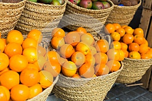 Pile of juicy oranges in wicker baskets on market counter