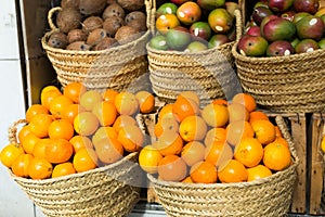 Pile of juicy oranges in wicker baskets on market counter