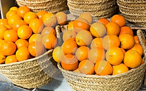 Pile of juicy oranges in wicker baskets on market counter
