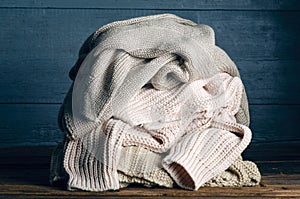 Pile of knitted warm clothes on wooden background, sweaters, knitwear