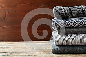 Pile of knitted winter clothes on wooden background, sweaters, knitwear