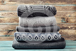 Pile of knitted winter clothes on wooden background, sweaters, knitwear