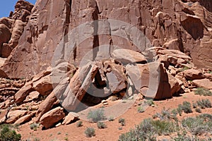 A pile of large boulders made of Entrada Sandstone in front of a wall of rock in Arches National Park, Moab, Utah