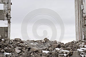 A pile of large gray concrete fragments with protruding fittings against a cloudy sky