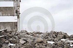 A pile of large gray concrete fragments with protruding fittings against a cloudy sky
